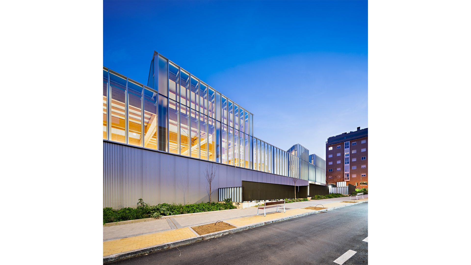 Bioclimatic architecture with nighttime lighting, wooden interior, and exterior curtain wall at the Francisco Umbral Library in Madrid