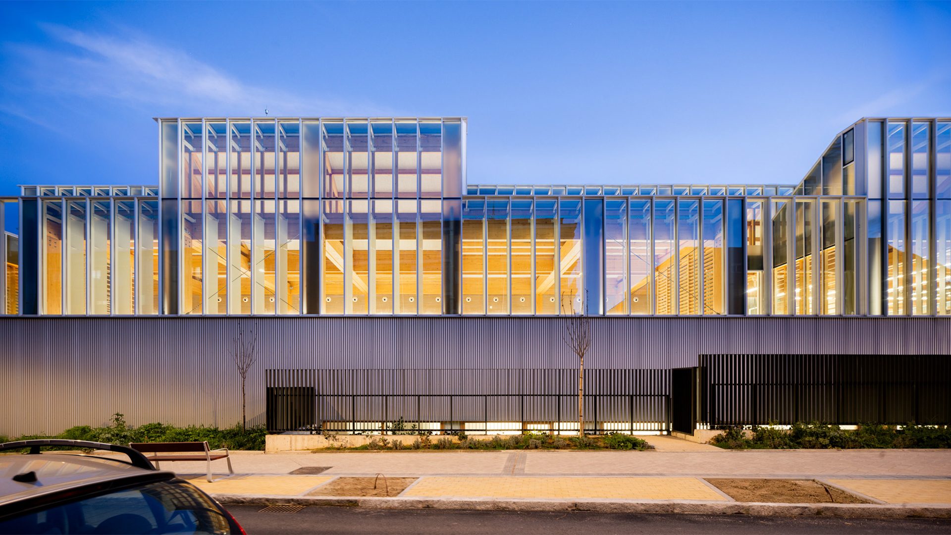 Bioclimatic architecture with nighttime lighting, wooden interior, and exterior curtain wall at the Francisco Umbral Library in Madrid